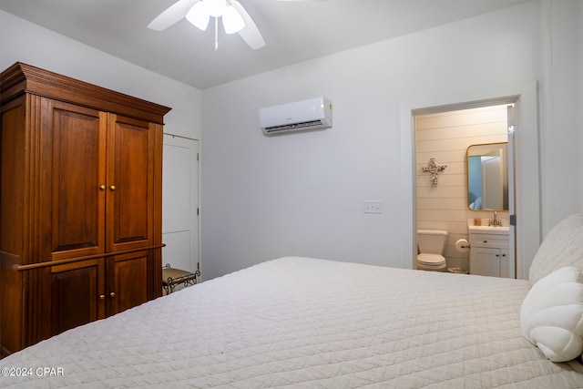 bedroom featuring connected bathroom, a wall unit AC, and ceiling fan