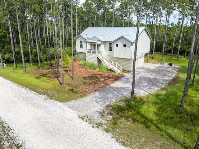 view of front of home with board and batten siding, stairs, metal roof, a garage, and driveway