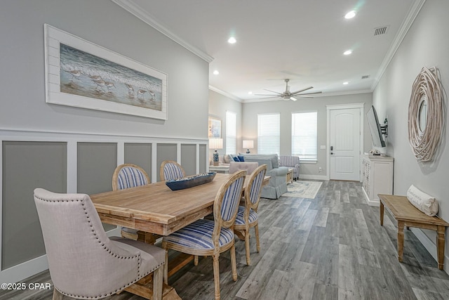 dining room with crown molding, recessed lighting, visible vents, a decorative wall, and wood finished floors