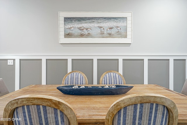 dining space with a decorative wall and wainscoting