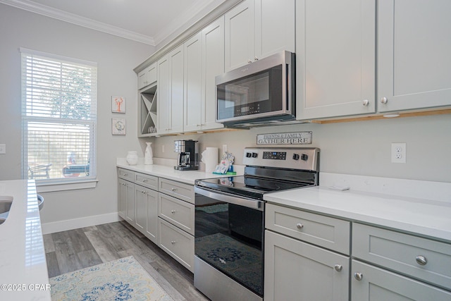 kitchen with baseboards, light wood-style flooring, stainless steel appliances, crown molding, and light countertops