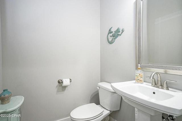 bathroom with baseboards, a sink, and toilet