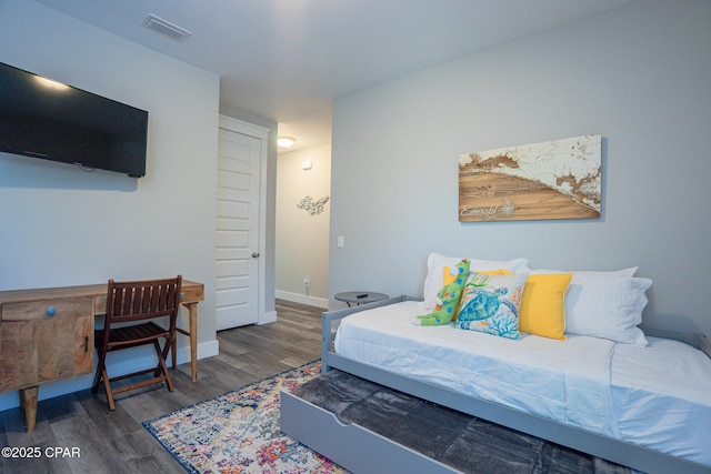 bedroom with wood finished floors, visible vents, and baseboards