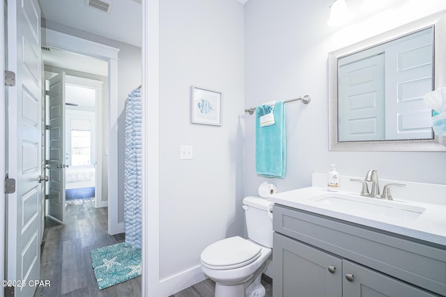 bathroom featuring toilet, wood finished floors, vanity, visible vents, and baseboards