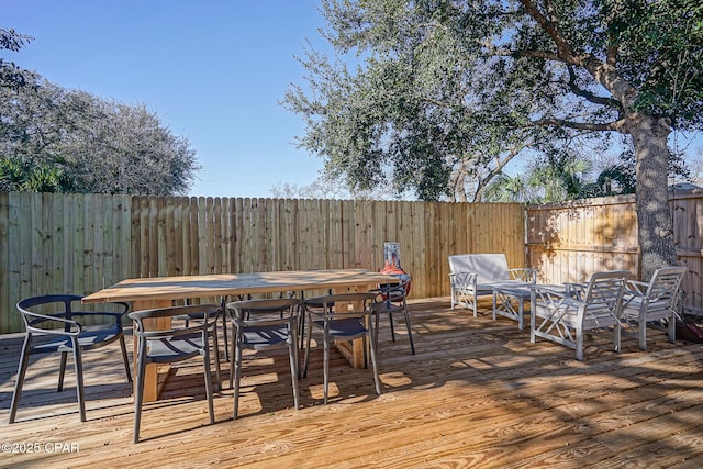 deck with outdoor dining area and a fenced backyard