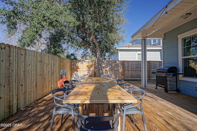 wooden deck with a fenced backyard, outdoor dining area, and area for grilling