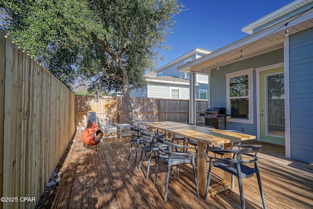 deck with outdoor dining area, grilling area, and a fenced backyard