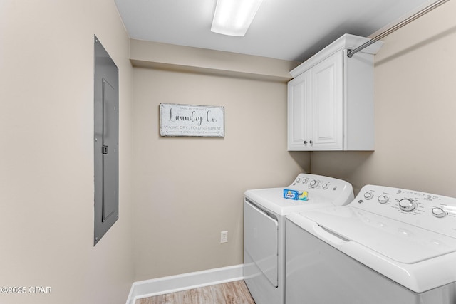 laundry area with cabinets, electric panel, washer and clothes dryer, and light hardwood / wood-style flooring