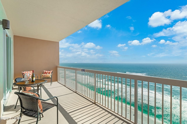 balcony with a water view and a view of the beach