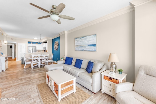 living room featuring crown molding, ceiling fan with notable chandelier, and light wood-type flooring