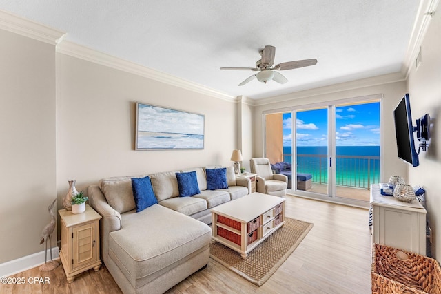 living room featuring ceiling fan, ornamental molding, a textured ceiling, and light wood-type flooring