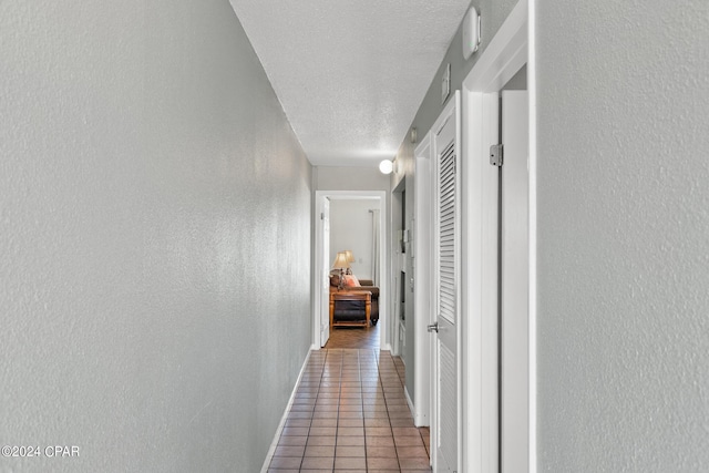 8743 Thomas Dr Unit 212, Panama City Beach, FL 32408 - hall featuring tile patterned flooring, a textured ceiling, a textured wall, and baseboards