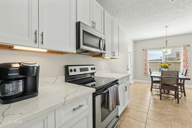 kitchen featuring appliances with stainless steel finishes, decorative light fixtures, white cabinetry, light stone countertops, and a textured ceiling