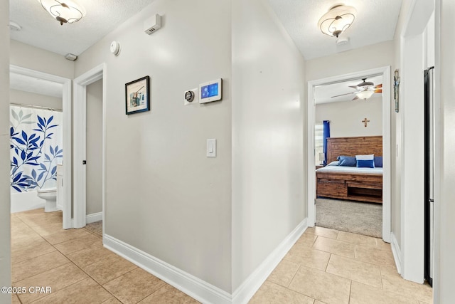 hallway featuring light tile patterned floors and a textured ceiling