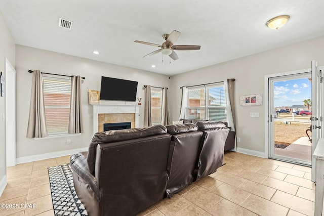 living room featuring a tile fireplace, light tile patterned flooring, and ceiling fan