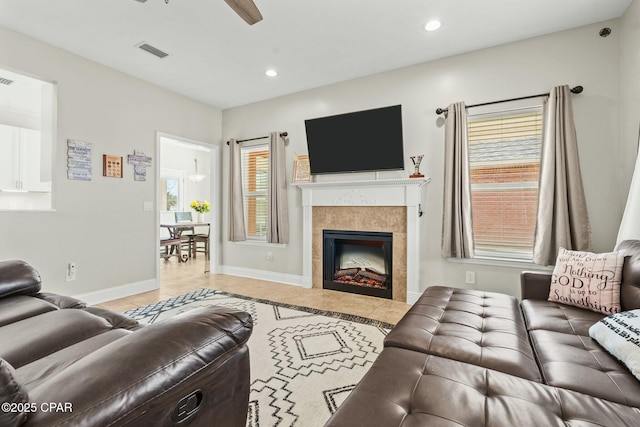 living room with ceiling fan and a tile fireplace