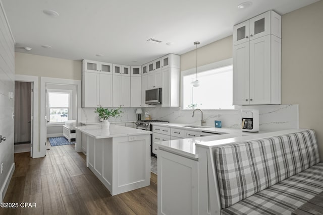 kitchen featuring pendant lighting, sink, appliances with stainless steel finishes, a center island, and white cabinets