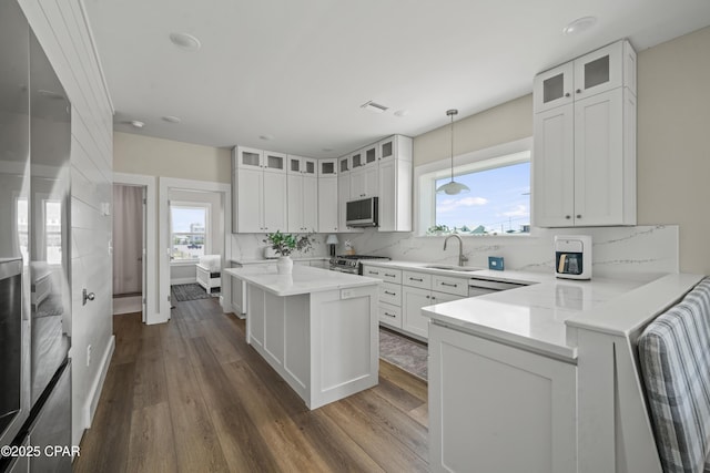 kitchen featuring hanging light fixtures, stainless steel appliances, sink, and white cabinets