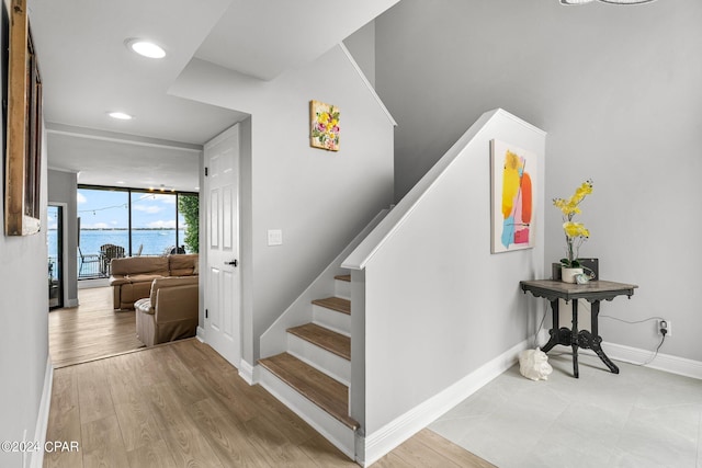 stairway featuring a water view, a wall of windows, and wood-type flooring