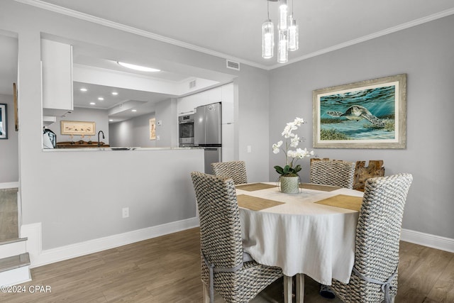 dining space featuring sink, crown molding, and dark hardwood / wood-style floors