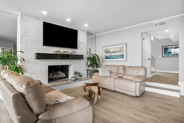 living room featuring a fireplace, ornamental molding, and light wood-type flooring