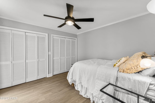 bedroom with crown molding, ceiling fan, multiple closets, and light hardwood / wood-style floors