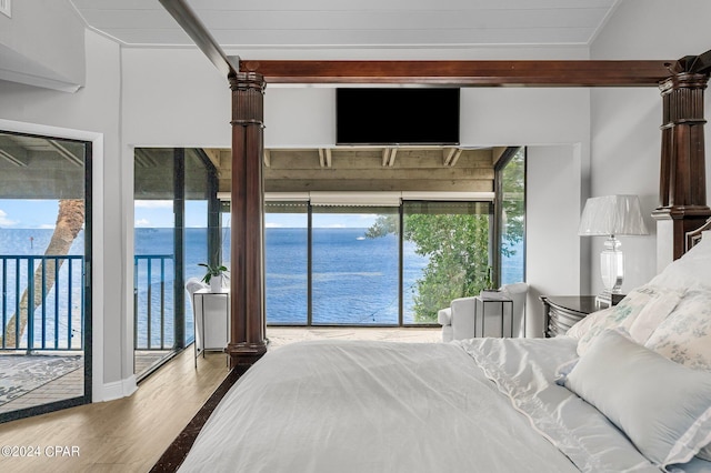 bedroom with beam ceiling, access to exterior, and hardwood / wood-style flooring