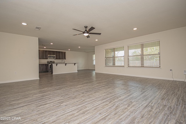 unfurnished living room featuring ceiling fan, a textured ceiling, and light hardwood / wood-style floors