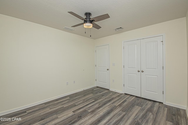 unfurnished bedroom featuring ceiling fan, dark wood-type flooring, a closet, and a textured ceiling