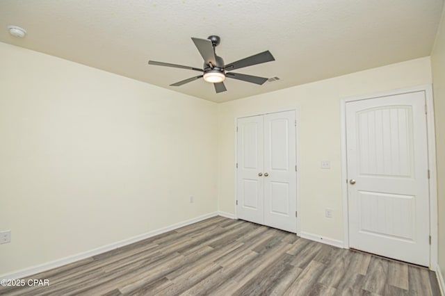 unfurnished bedroom with ceiling fan, hardwood / wood-style floors, a closet, and a textured ceiling