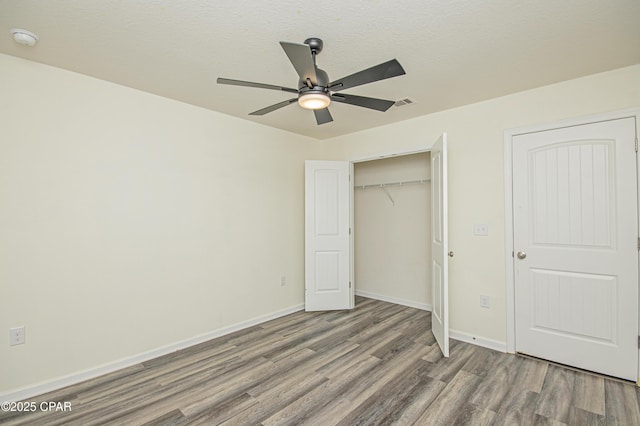 unfurnished bedroom featuring ceiling fan, hardwood / wood-style floors, a textured ceiling, and a closet