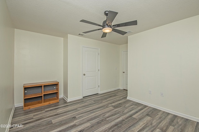 empty room featuring dark wood-type flooring, ceiling fan, and a textured ceiling