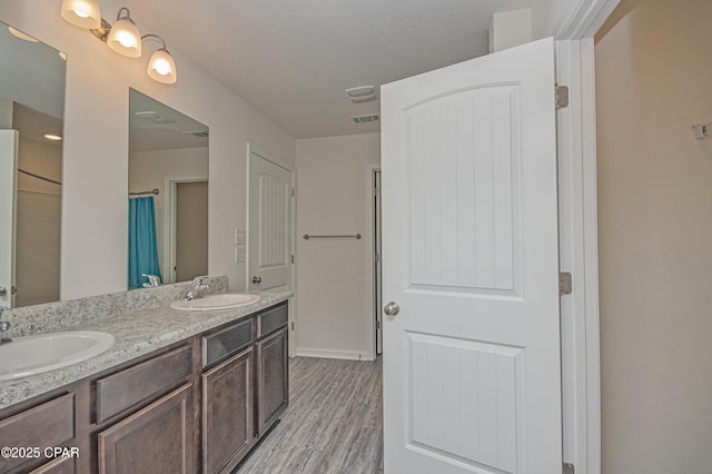 bathroom with vanity, wood-type flooring, and a textured ceiling