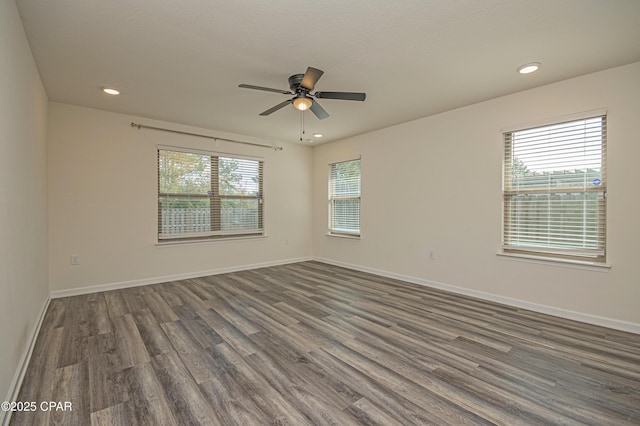 empty room with ceiling fan, a healthy amount of sunlight, and dark hardwood / wood-style floors