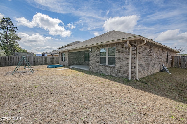 rear view of property featuring a patio area and a playground