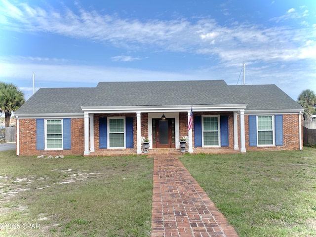 view of front of property featuring brick siding, a front yard, and roof with shingles