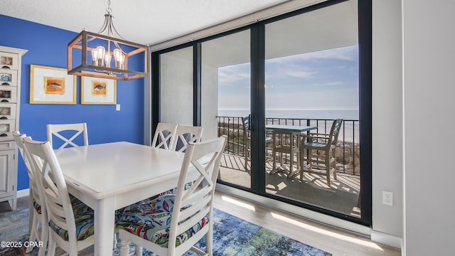 dining area with a water view, hardwood / wood-style floors, and a notable chandelier