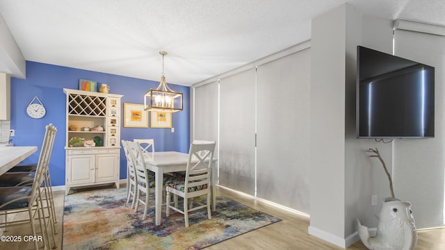 dining space with wood-type flooring, a notable chandelier, and a textured ceiling