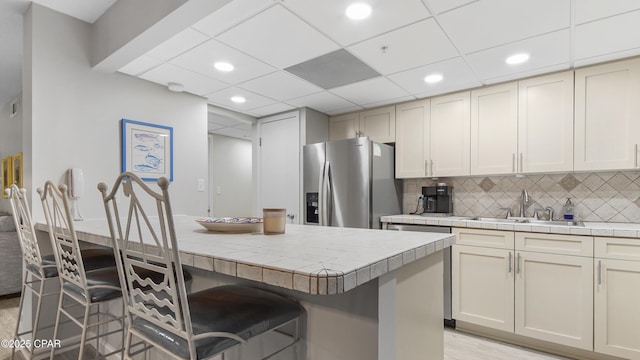 kitchen featuring tasteful backsplash, sink, a kitchen breakfast bar, tile counters, and stainless steel fridge with ice dispenser