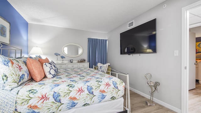 bedroom featuring light hardwood / wood-style flooring and a textured ceiling