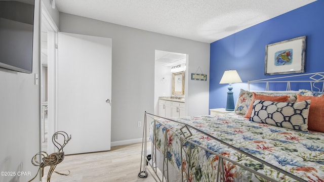 bedroom with connected bathroom, sink, a textured ceiling, and light wood-type flooring