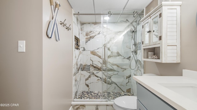 bathroom featuring vanity, a shower with door, and toilet