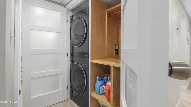 clothes washing area with stacked washer / dryer and light hardwood / wood-style flooring