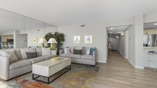 living room featuring light hardwood / wood-style flooring and a textured ceiling