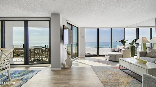 living room with light wood-type flooring, a textured ceiling, and a wall of windows