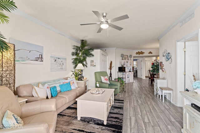 living room featuring visible vents, ornamental molding, a ceiling fan, and wood finish floors