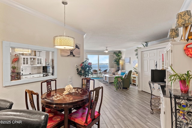 dining space with light wood-type flooring, ornamental molding, and a ceiling fan