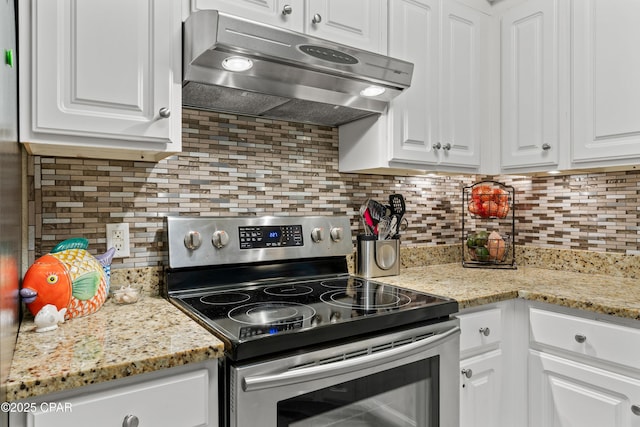 kitchen with light stone counters, stainless steel electric range oven, backsplash, white cabinetry, and under cabinet range hood