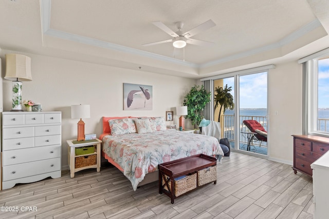 bedroom with crown molding, access to outside, a raised ceiling, and wood tiled floor