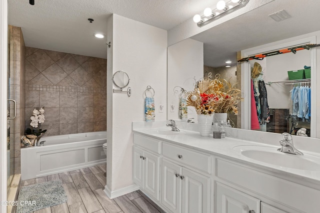 full bath featuring wood tiled floor, a textured ceiling, and a sink